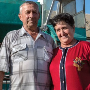 Man and woman standing in front of tractor.
