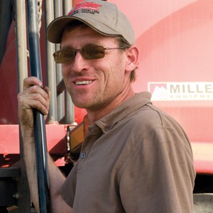 Man standing beside farm implement.