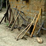 Small farmer's equipment and tools beside a shed