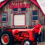 woman standing outside farm with tractor