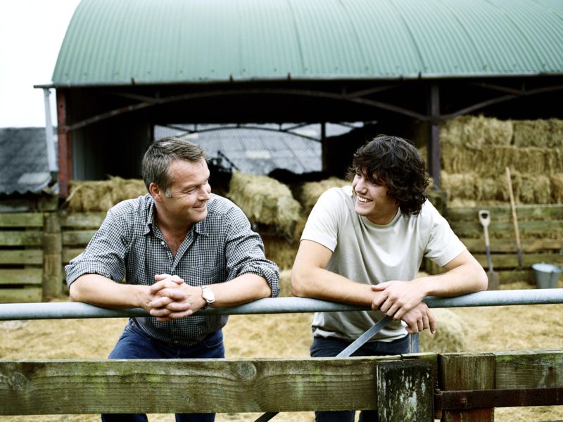 Farmer and His Son Leaning on a Gate in a Paddock on a Farm