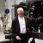Robert Ciecko, vice-president of Hesston manufacturing, discusses the assembly procedure for these Massey Ferguson swathers while guiding journalists through the hay tool and combine assembly plant.