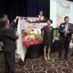 The new cover of the Real Dirt on Farming was unveiled at the Farm & Food Care Harvest Gala last week. Doing the unveiling was Farm & Food Care chair Brian Gilroy, left, Christine Schoonderwoerd, vice chair, and representing funder Wallenstein Feed & Supply Ltd., Pierre Petelle, president of CropLife Canada. Farm & Food Care Executive Director Kelly Daynard is at the podium. Photo courtesy Farm and Food Care.