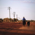 A stockman rides his horse as he leads another down a road towards the cattle yards in the outback town of Windorah, Queensland, Australia. The Australian agriculture sector says lenders need more oversight and better understanding of the ups and downs of agriculture.