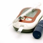 Close up of syringe for insulin and Glucose meter with lancet for check blood sugar level on white background using as Medicine, diabetes, glycemia, health care and people concept.