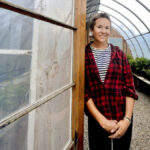 Amy Kitchen stands at the door to a greenhouse at Sideroad Farm.