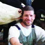 Portrait of Ben Loewith. next to cow.