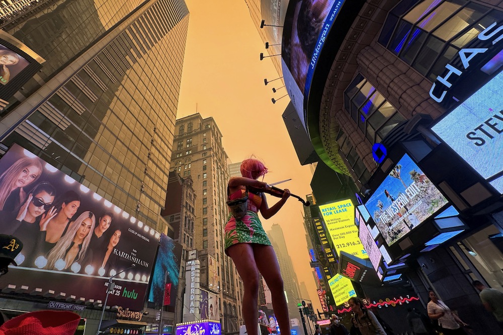 A climate change activist plays a violin in New York City’s Times Square as Manhattan is shrouded in haze and smoke which drifted south from wildfires in Canada, on June 7, 2023. (Photo: Reuters/Maye-E Wong)
