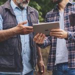 farmers in a field looking at a smart tablet
