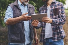 farmers in a field looking at a smart tablet