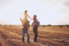 Cheerful siblings, sisters, enjoying a summer day in a wheat field with a father and grandfather.