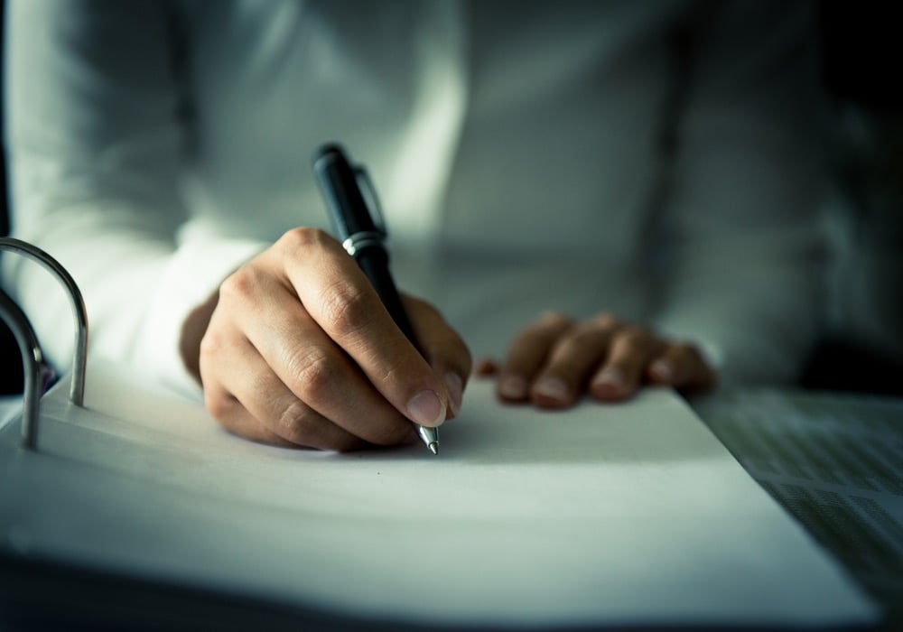 Closeup view of a human hand writing on a piece of paper