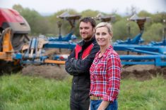 young man and woman farmers with a tractor and cultivator in the background
