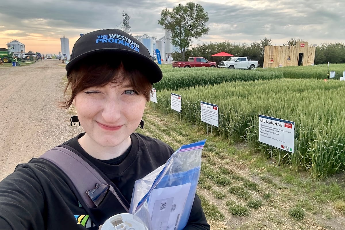 youn woman wearing a ball cap with wheat plots in the background at a farm show