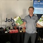 Joel Merkosky, president of Johnston’s Grain, shows off some of the firm’s brochures at its booth at the Ag in Motion 2025 show in Langham, Sask.Joel Merkosky, president of Johnston’s Grain, attended Ag in Motion 2025 to explain his company’s move into regenerative agriculture. Photo: Sean Pratt
