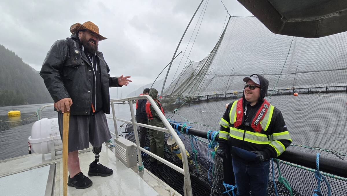 Dallas Smith, left, speaking to a Mowi salmon farm worker on a fish farm in Kitasoo Xai’xais territory, May 26, 2025.