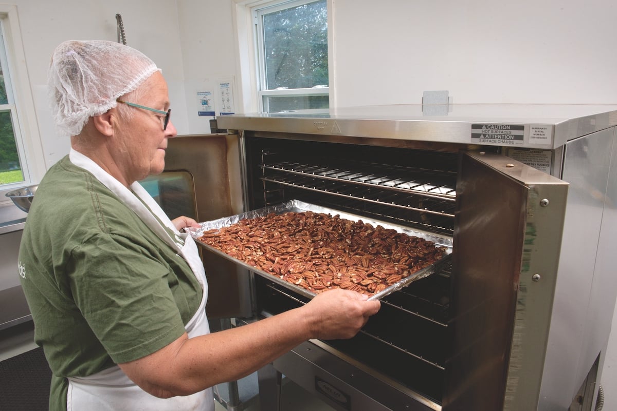 Elisabeth Burrow removing a pan of roasted nuts rom her oven