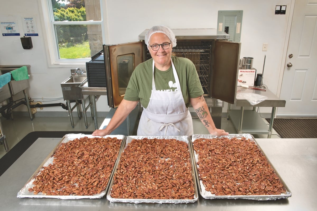 Elisabeth Burrow standing by a table with pans of her roasted nuts