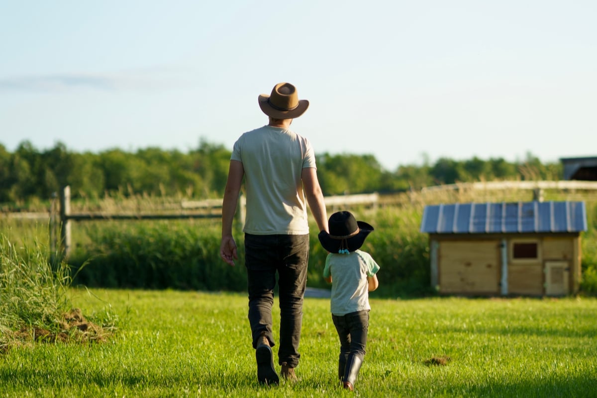 Father and child walking together on a green farm field