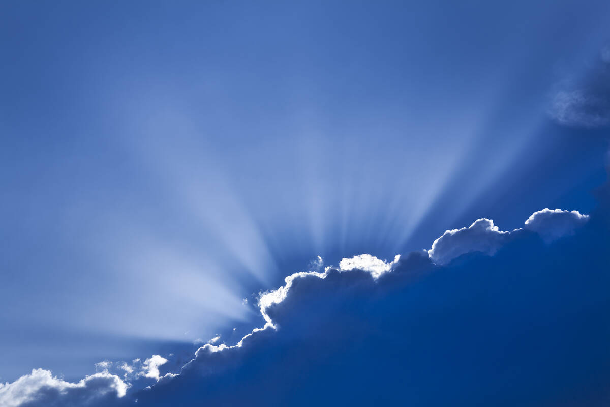 Sunrays burst above cloud, with dramatic rim lighting.
