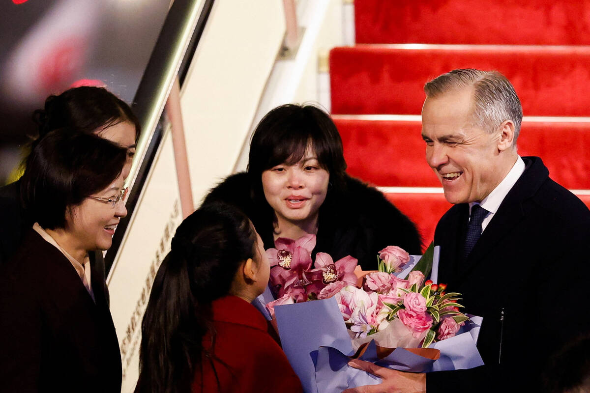 Canada’s Prime Minister Mark Carney receives flowers from Lu You Ci, 11, upon his arrival at Beijing Capital International Airport, during the first visit by a Canadian Prime Minister to China since 2017, in Beijing, China January 14, 2026.  Photo: REUTERS/Carlos Osorio
